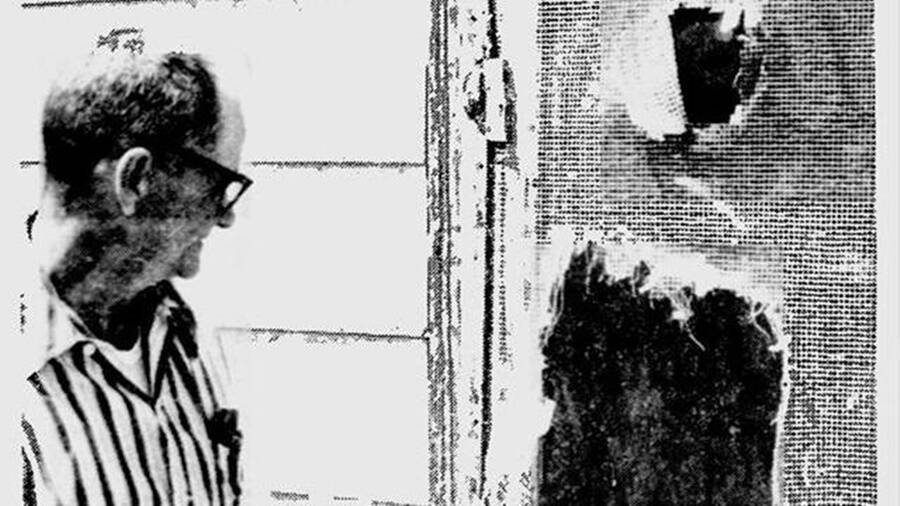 Генри МакДэниел смотрит на порванную сетчатую дверь своего дома после встречи с Энфилдским монстром 